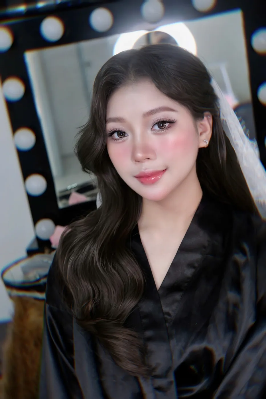 Bridal-style glam makeup in front of a lit mirror